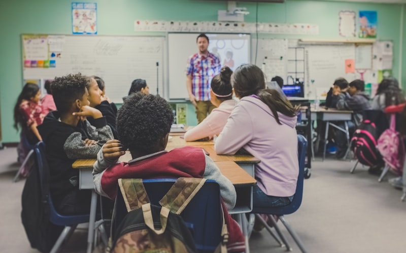Students seated at desks facing a teacher in a classroom