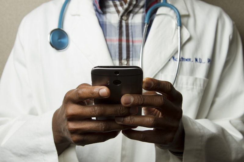 Clinician using a smartphone while wearing a white coat